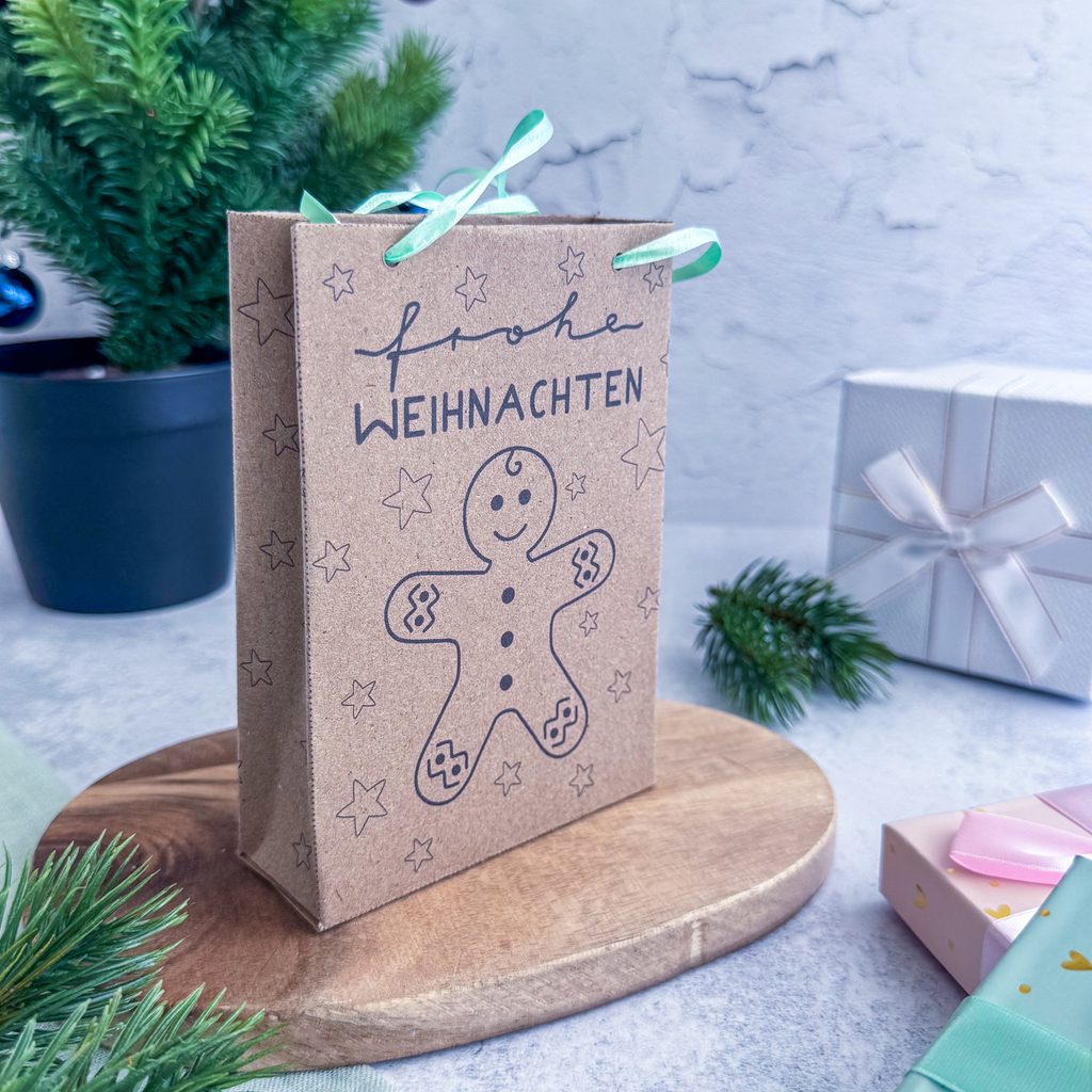 Kleine Geschenktüte aus Papier zu Weihnachten. Die Weihnachtstüte hat einen Lebkuchenmann als Motiv und im Hintergrund Sterne. Die weihnachtliche Geschenktüte zum Ausdrucken ist ideal für Kleinigkeiten wie Gutscheine, Schmuck oder Süßigkeiten.