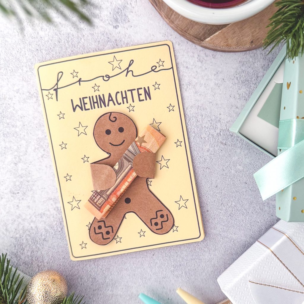 Geldgeschenk zu Weihnachten. Eine Weihnachtskarte mit Lebkuchenmann, der einen Geldschein in den Händen hält